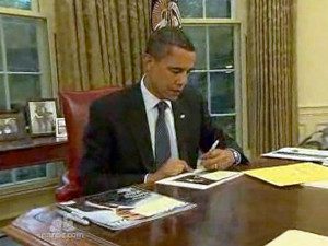 President Obama working at his desk in the Oval Office