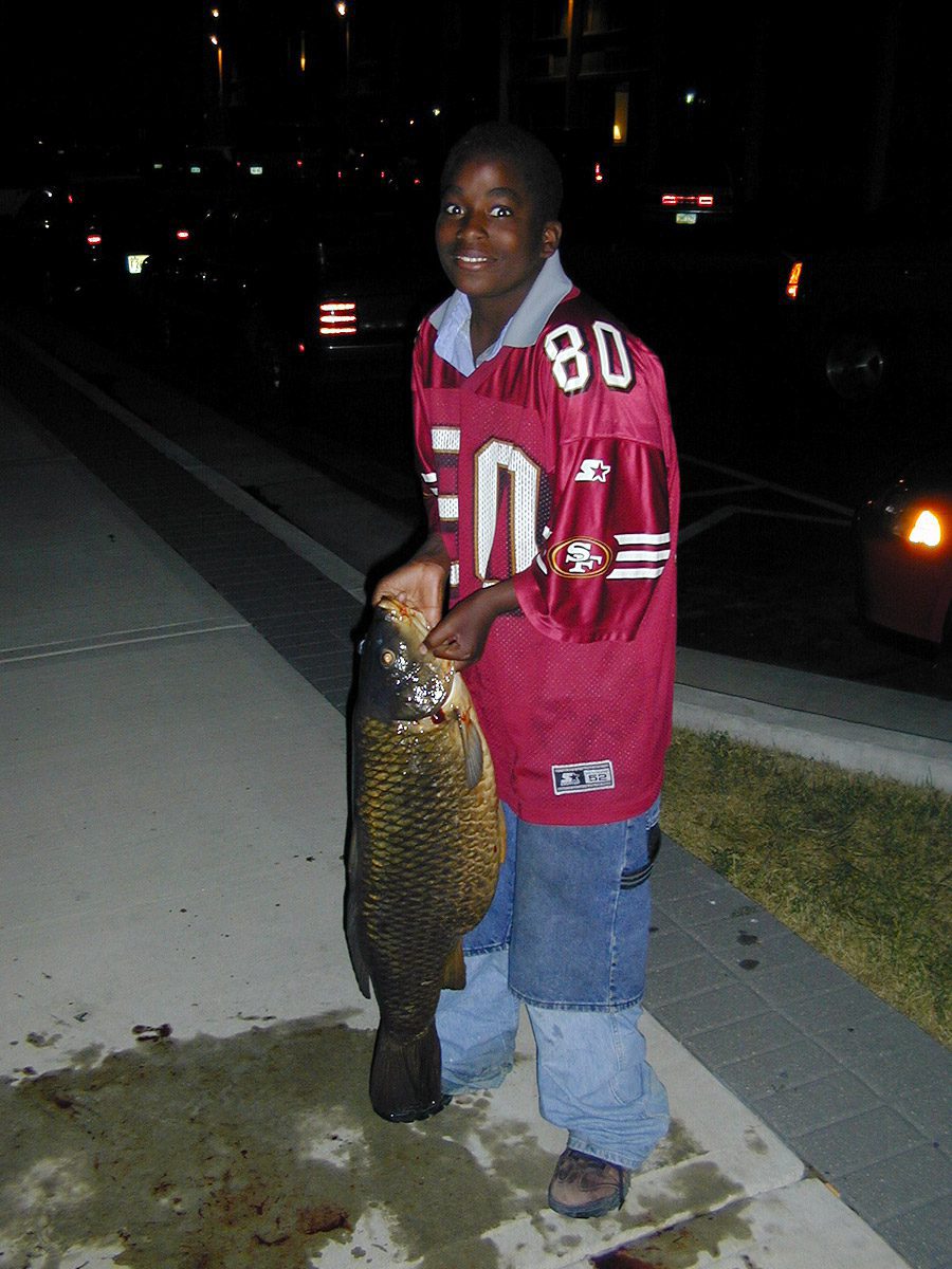 Young fisherman with large carp fish at Kenosha, Wisconsin harbor